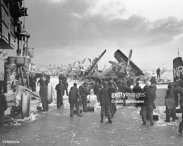 Crewmen aboard the aircraft carrier USS Essex clear the flight deck of snow. | Location: Near Korea.