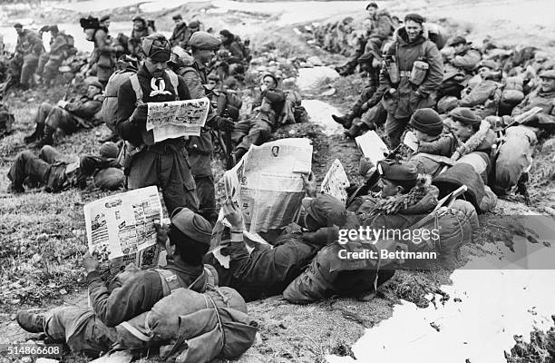 Korea: In a rest area near te front lines, Canadian soldiers eagerly scan the news from home while waiting for ordersto move up against Chinese Red...