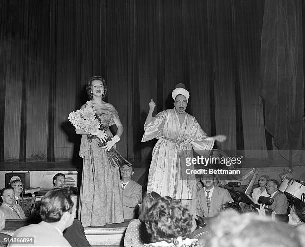 BeBe Shopp, Miss America 1948, clutches an armful of flowers as she is introduced to the crowd at the Folies Bergere in Paris by entertainer...