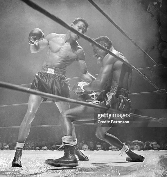 Sugar Ray Robinson throws a powerful punch to Tommy Bell's midsection during their match.