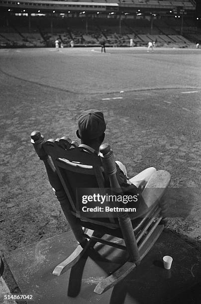 Satchel Paige, newly signed pitcher for the Kansas City Athletics, watches a Kansas City-Washington game from the comfort of a rocking chair in the...