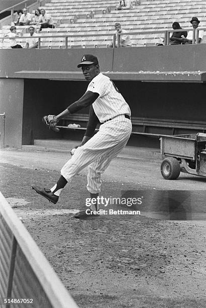 Working as a pitching coach for the Atlanta Braves, veteran pitcher Satchel Paige pitches in the bullpen. Paige played in the Negro Leagues for many...
