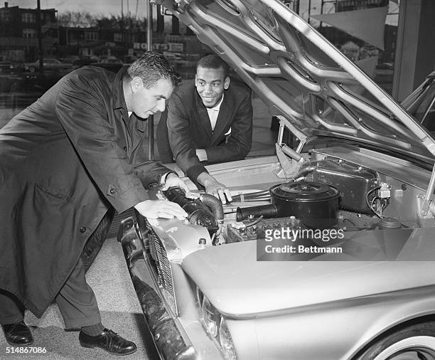 Chicago Cubs' star shortstop Ernie Banks , working in the off-season as a car salesman, looks under the hood of a car with a customer. Chicago,...