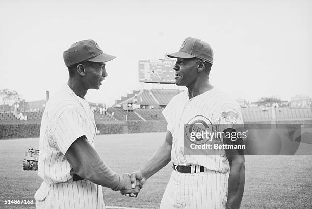 New member of Chicago Cubs coaching staff, John O'Neil congratulates Cubs first baseman Ernie Banks after Banks slammed out 3 homers in the game with...