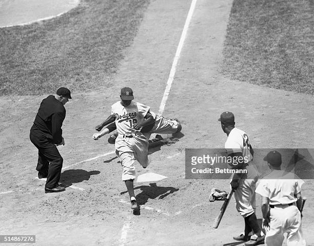 Dodger Jim Gilliam beats Del Crandall's tag at the plate, during a game against the Milwaukee Braves at Ebbets Field. 1953.