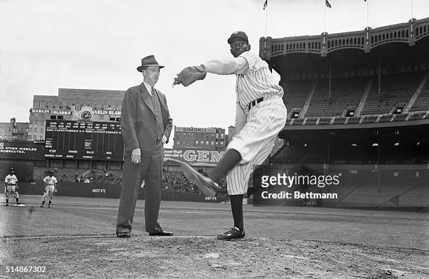 Baseball Hall of Famer Grover Cleveland Alexander stands on the pitcher's mound at Yankee Stadium and watches pitcher Satchel Paige at work. Paige is...