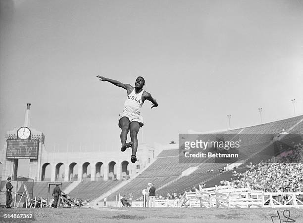 Long jumper Jackie Robinson leaps through the air at a college track meet in the Los Angeles Coliseum. 1940.