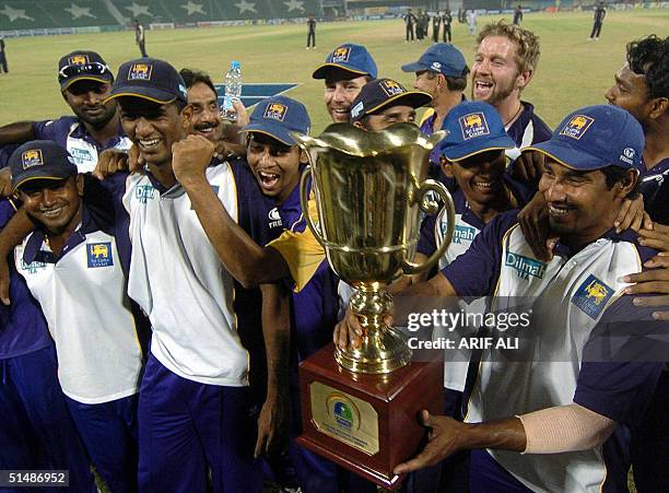 Sri Lankan cricket team players celebrate with the winners trophy of tri-series tournament at the Gaddafi stadium in Lahore,16 October 2004. Left...