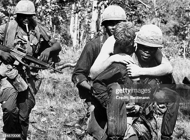 Wounded soldier is carried by members of the 1st Calvary Division while under heavy shelling during Operation Junction City about two miles from the...