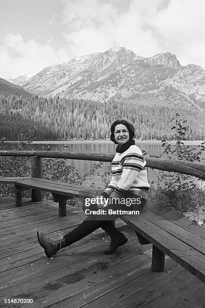 Jackson Lake, WY: Mrs. Lyndon B. Johnson, in climbing boots and a sweater, relaxes on the front porch of the recreation hall at the Rockefeller...