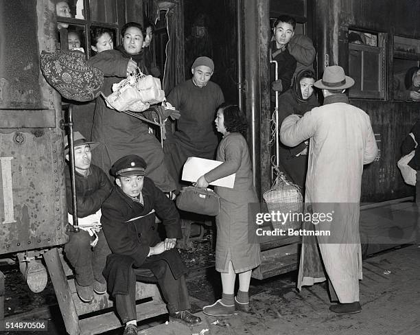 Nanking, China: War refugees and people going home for New Year's jam a train at Nanking to the point of overflow. Note how the officer has tied...