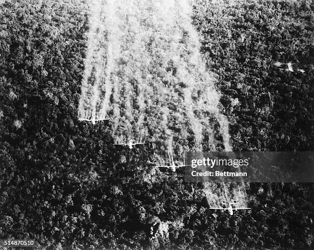 Tan Son Nhut, South Vietnam: A flight of four United States Air Force Ranch Hand C-123s spray a Viet Cong jungle position near here with a...