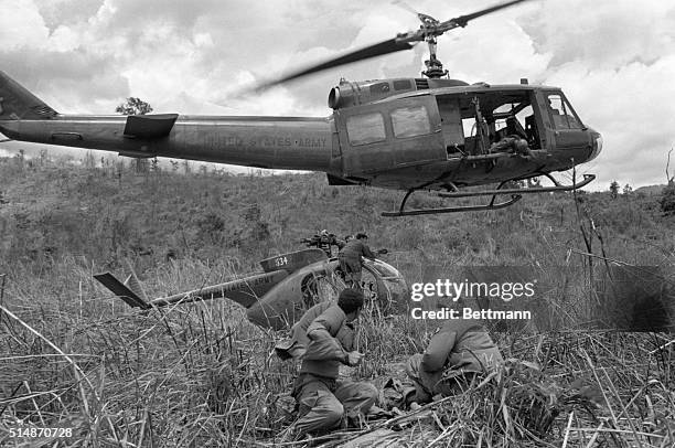 Near Khe Sanh, South Vietnam: U.S. Soldiers prepare a grounded observation helicopter for recovery as a "Huey" hovers overhead waiting to pluck it...