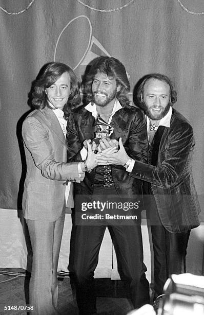 Los Angeles, CA: Grammy winners 2/15 the Bee Gees, brothers Robin, Barry and Maurice Gibb hold their Grammy for their Album of the Year Award,...