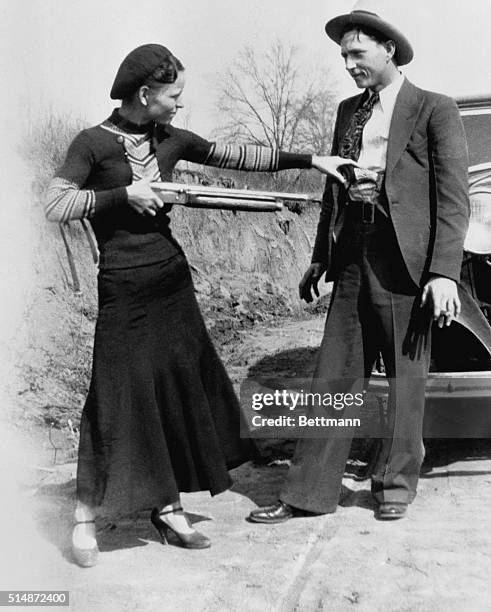 American outlaw Bonnie Parker, playfully points a shotgun at her partner Clyde Barrow in 1932. The two were well-known wanted criminals during a two...