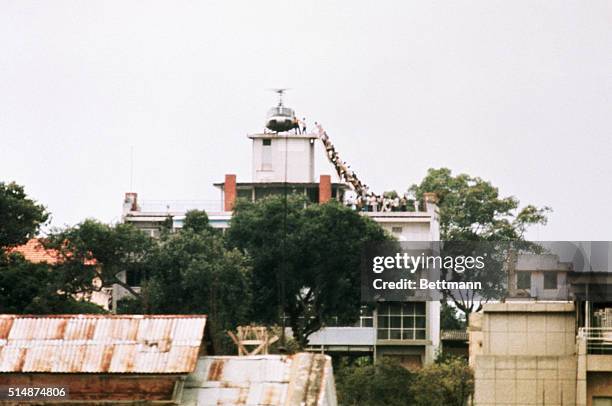 Employee helps Vietnamese evacuees onto an Air America helicopter from the top of 22 Gia Long Street, a half mile from the U.S. Embassy.