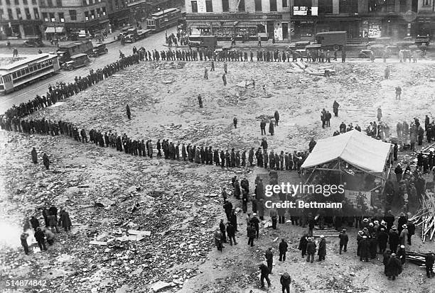 Unemployed bread lines; despite a heavy rain, these poor unfortunates, jobless and moneyloos , wait in line at Grand and Christie Streets in NYC for...