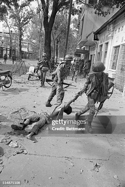 South Vietnamese soldiers drag the body of a dead Vietcong guerrilla away from a government building during a rash of Vietcong attacks in Saigon...