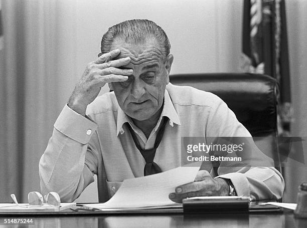 Weary-looking President Johnson looks at documents on his desk in the Cabinet Room of the White House. He is preparing an address on Vietnam.