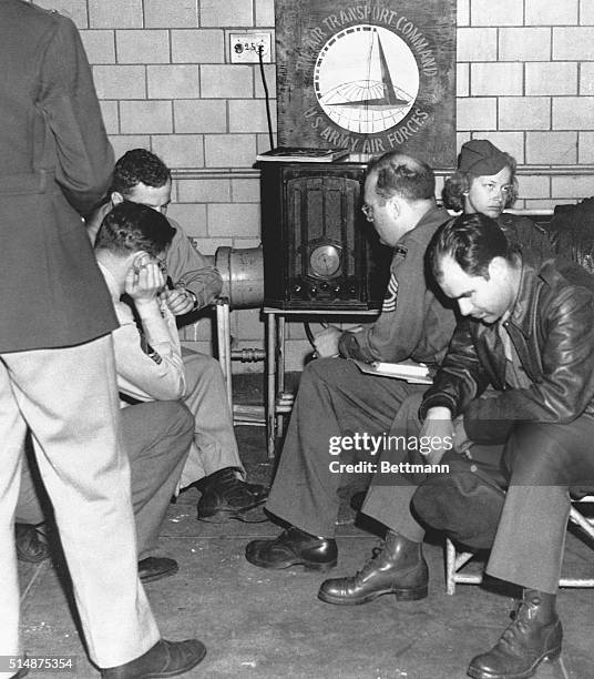 Military staff at La Guardia Field in New York gather around a radio and listen intently as President Franklin D. Roosevelt prays for the Allied...