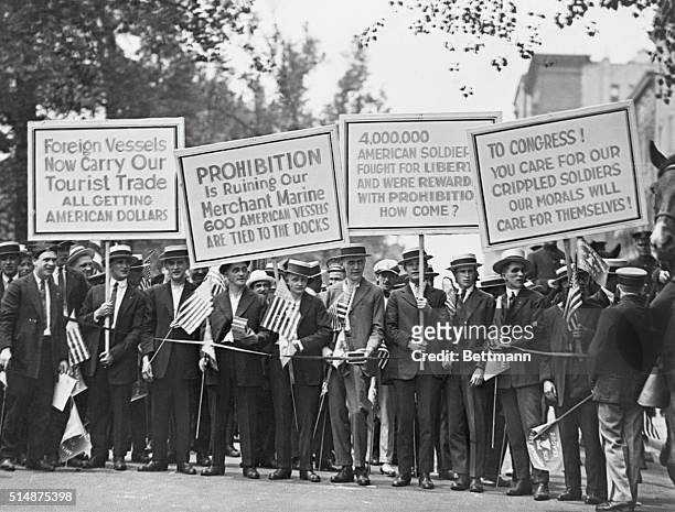 Protesters carrying signs about the negative effects of prohibition on international trade, returning soldiers and morals.