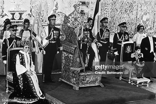 The Shah of Iran, seated on the peacock throne, is flanked by Queen Empress Farah and their son, Crown Prince Reza. After the coronation ceremony in...