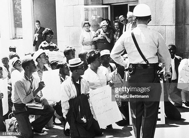 Arrested for parading without a permit, African American protesters kneel on a sidewalk in Birmingham, Alabama.