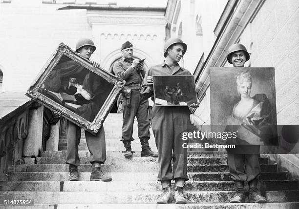 Fussen, Germany: While a lieutenant checks his list in the background, 7th army soldiers carry three valuable paintings down the steps of...
