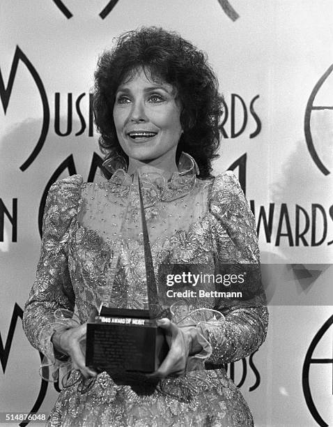 Country music singer Loretta Lynn holds a special award given for her long time contributions at the 1985 American Music Awards.