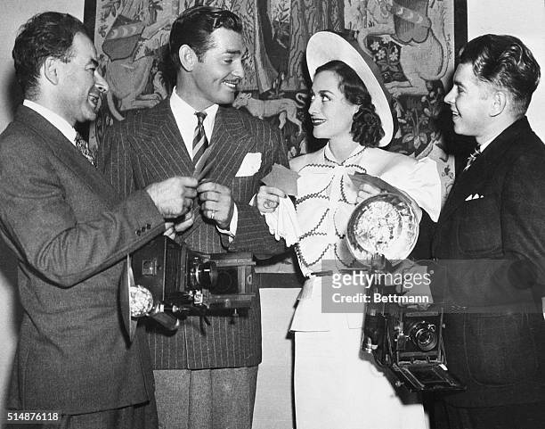 Actors Clark Gable and Joan Crawford stand in between two photographers, Hyman Fink and Jack Albin, on September 20, 1936. They were among the first...
