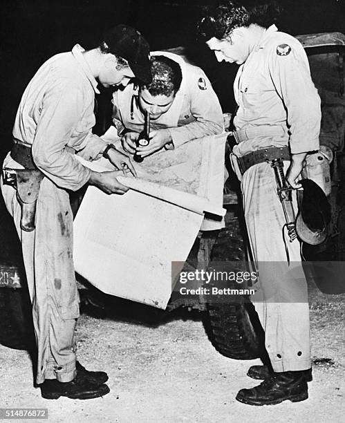 Pacific Area: Men who helped drop the second war-stopping atomic bomb on Nagasaki, Jap city, are shown here studying a map of their objective shortly...