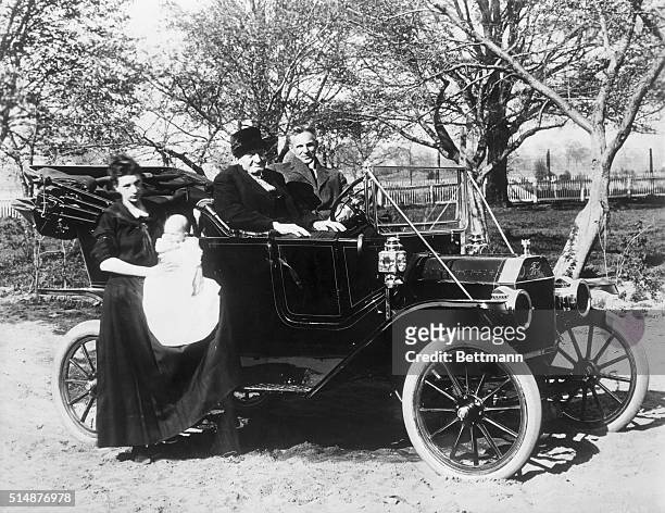 Henry Ford seated in a Model T on his Dearborn farm with his uncle Henry and possibly a great-niece