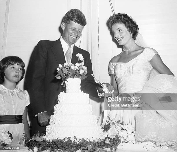 Newport, RI: Democratic Senator John F. Kennedy and his bride, the former Jacqueline Lee Bouvier, cut their wedding cake after their marriage...