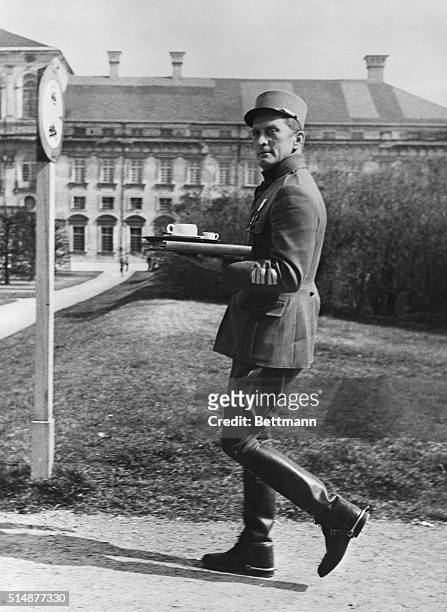 Munich, Germany: American movie star Kirk Douglas, attired in the uniform of a French Colonel carries his tray with a cup of coffee during a break in...