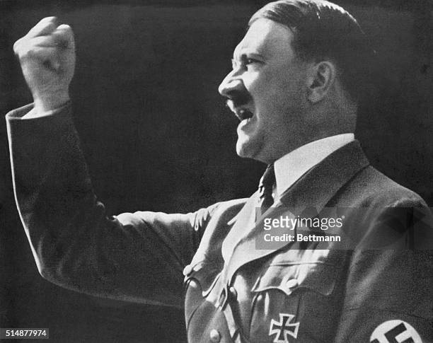 Adolf Hitler raises a defiant, clenched fist during a speech.