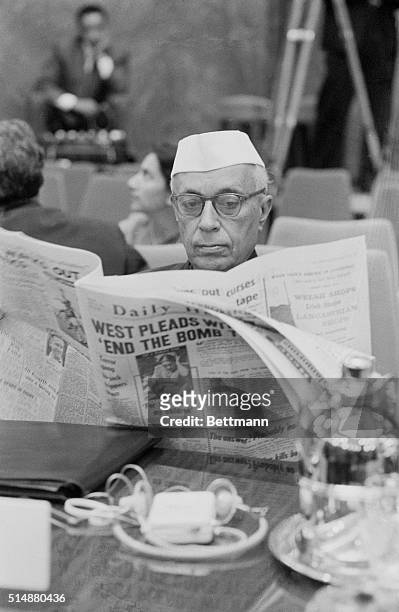 Indian Prime Minister Jawaharial Nehru reads an English newspaper while waiting for the morning session of a conference of non-aligned nations.