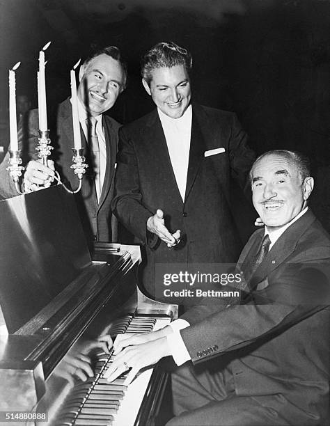 Hollywood, CA: Piano impressario Wlasziu Liberace takes a back seat and lets film producer Jack L. Warner tickle the ivories as they took time out...