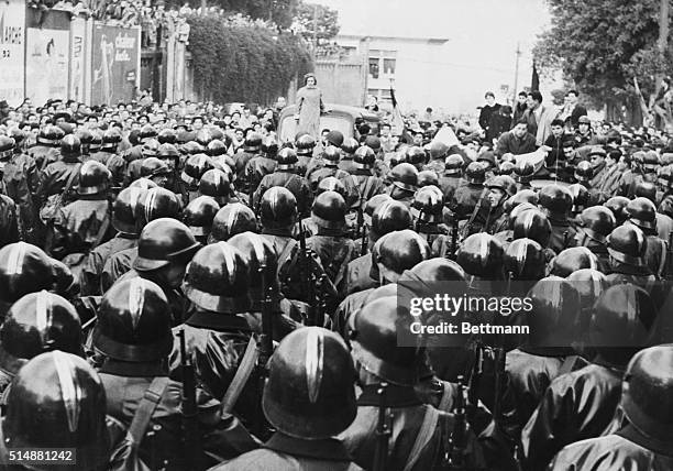 Algiers, Algeria: A lone woman demonstrator, standing on rear of car and other members of an unruly Algerian mob hold off a large force of police of...