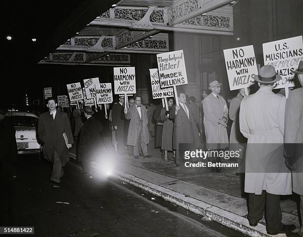 New York, NY: Pickets from various Jewish and Labor organizations carry protesting signs the appearance of the Berlin Philharmonic Orchestra at...