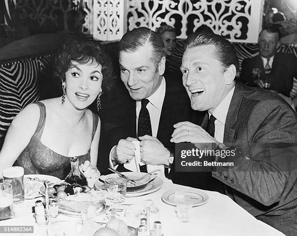 Gina Lollobrigida with Laurence Olivier and Kirk Douglas during her farewell party at the El Morocco in New York City.