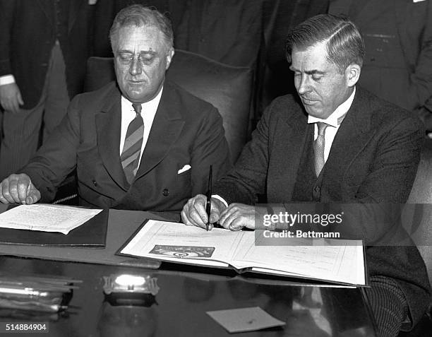 President Roosevelt and Secretary of Agriculture Henry Wallace sign a bill.