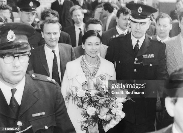 Carrying a large bouquet of flowers, British Ballerina Dame Margot Fonteyn is escorted through crowds upon her arrival at London Airport. Dame Margot...