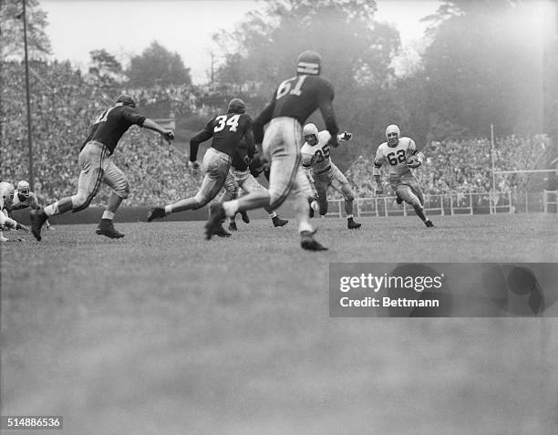 Charlie Trippi, #62, runs to the right seeking a pass receiver as Mel Bray blocks out an Alabama player. Trippi couldn't find a receiver and elected...