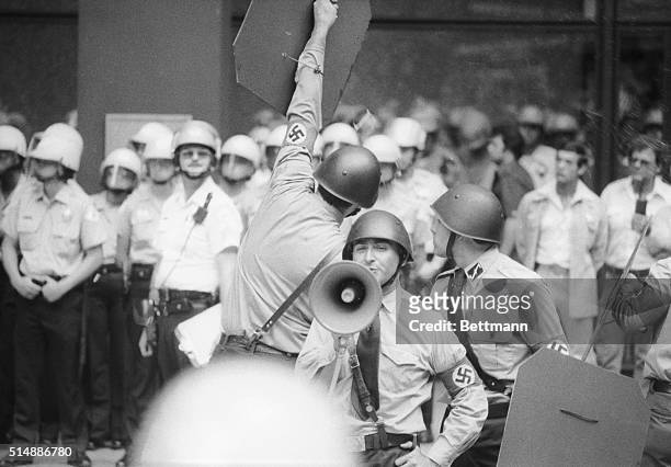 Nazi leader Frank Collin speaks in a bullhorn as another Nazi uses a shield to deflect an egg thrown by an anti-Nazi counter-demonstrator at the...