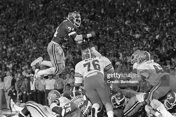 Football player Herschel Walker, number 34, grabs the football from the air while playing for the University of Georgia football team.