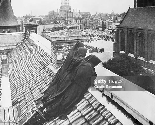 Three Nuns Watching a Military Show From a Slanted Rooftop at Delft, Holland. A photograph won second prize in an international photo contest...