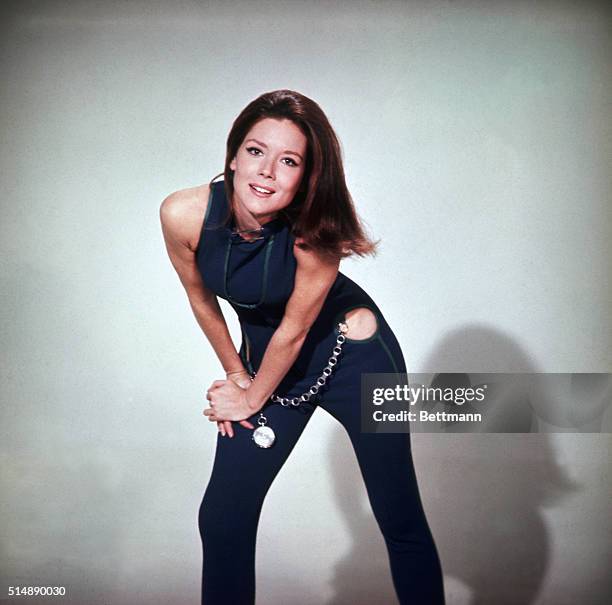 Length pose of Diana Rigg as Emma Peel in The Avengers. In this shot, Rigg is wearing a blue, one piece pants suit with cut out hips and an oversized...