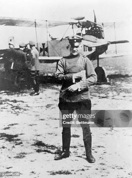 German fighter ace Manfred von Richthofen, known as the Red Baron, stands near a Fokker DVII biplane.