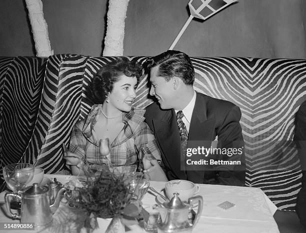 New York: Actress Elizabeth Taylor with Conrad "Nicky" Hilton, Jr., seated in the zebra booth at Manhattan's posh nightclub, El Morocco, 154 E. 54th...