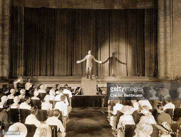 FAMOUS SCENE OF AL JOLSON IN THE 1927 WARNER BROS. FILM, "THE JAZZ SINGER." JOLSON IS ON STAGE IN BLACKFACE WITH SPOTLIGHT ON HIM. ORCHESTRAL PIT IS...
